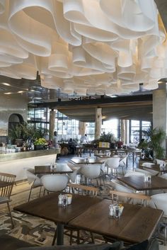 an empty restaurant with tables and chairs in front of large windows, hanging from the ceiling