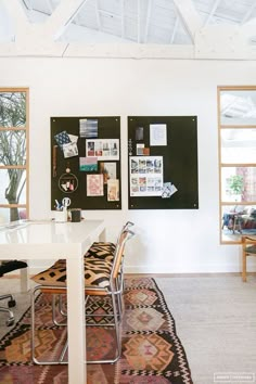 a white table and chairs in a room with two blackboards on the wall behind them