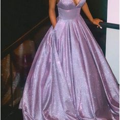 a woman in a purple ball gown standing on a stair case with her hand on the railing