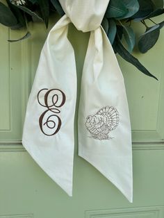 the front door is decorated with two white towels and green leaves, which are hanging from a metal hook