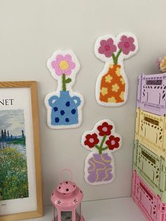 there are some crocheted flowers in vases on the wall next to a pink lantern