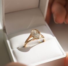 a person holding an engagement ring in a box with the light shining on it's side