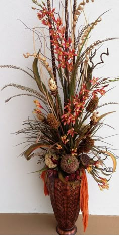 a vase filled with lots of different types of flowers and plants next to a wall