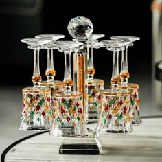 four glass candlesticks with colorful designs on them sitting on a table next to a mirror