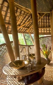 the inside of a bamboo hut with wicker furniture and flowers in vases on top