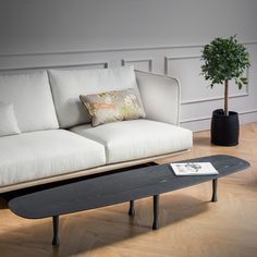 a white couch sitting next to a black skateboard on top of a wooden floor