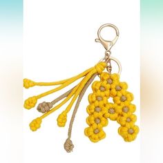 a yellow keychain with flowers is hanging on a white background and there are other items in the photo