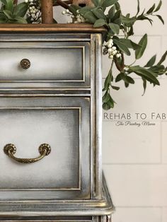 a silver and gold dresser sitting next to a planter with white flowers on it