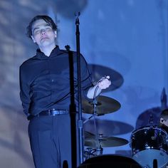 a man standing in front of a drum set