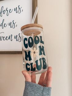 a person holding up a mason jar with the words cool mom club written on it