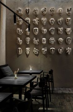 a wall with many masks hanging on it's sides and tables in front of them