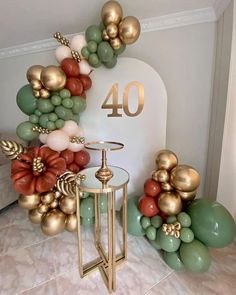 the balloon arch is decorated with gold, green and red balloons that spell out 40