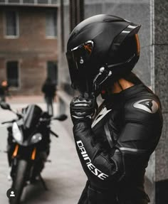 a person wearing a helmet standing next to a motorcycle