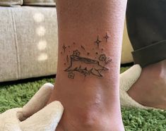 a woman's foot with a small tattoo on her left ankle and stars in the sky