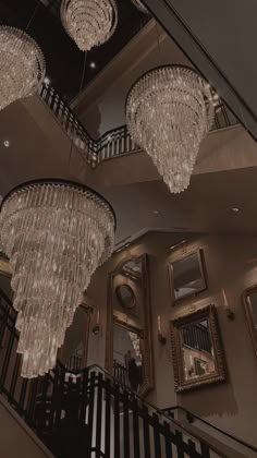 the chandeliers are hanging from the ceiling above the stairs in this elegant home