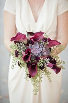 a bridal bouquet with purple flowers and succulents in the bride's hand