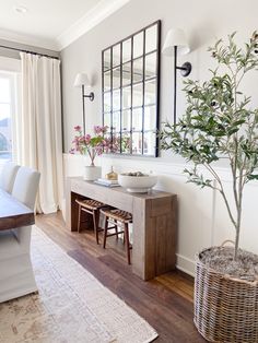 a dining room with a table, mirror and potted plant on the sideboard