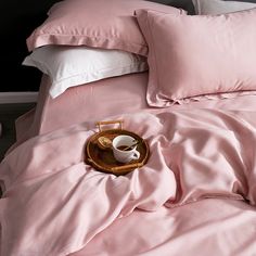 a tray with a cup and saucer sitting on top of a pink comforter