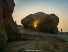 the sun shines brightly behind two large rocks