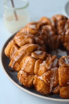 a bundt cake with icing on a plate next to a glass of milk