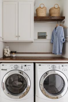 a washer and dryer in a white laundry room with open shelving on the wall