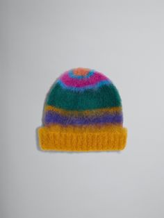 a multicolored knitted beanie hat on a white surface with a small hole in the middle