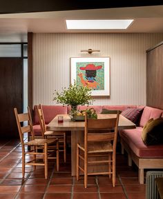 a dining room table with chairs and a bench in front of the wall that has a painting on it