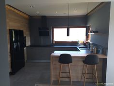 a kitchen with two stools next to a counter top and a refrigerator freezer