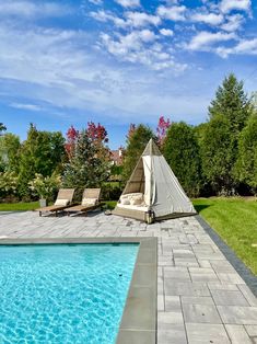 an outdoor swimming pool with lounge chairs and a teepee tent in the back yard