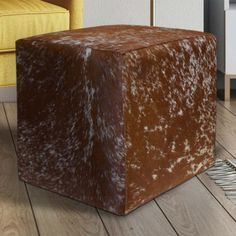 a brown and white stool sitting on top of a wooden floor next to a yellow chair