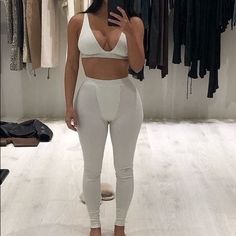 a woman taking a selfie in front of a mirror while wearing white leggings