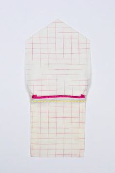 a piece of cloth with pink and yellow lines on it sitting on a white surface