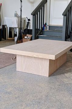 a wooden table sitting on top of a carpeted floor next to a stair case