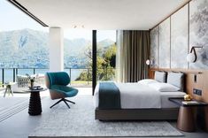 a bedroom with a bed, chair and table in front of a large window overlooking the mountains