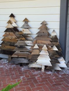 several wooden christmas trees are lined up against a wall