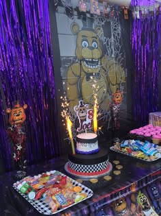 a birthday cake with lit candles on it and decorations around the cake are purple streamers