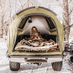 the back end of a truck with an open bed in it and a woman sitting inside