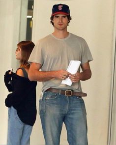 a man and woman standing next to each other in front of a door holding papers