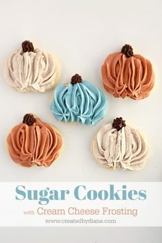 four sugar cookies with cream cheese frosting in the shape of pumpkins on a white background