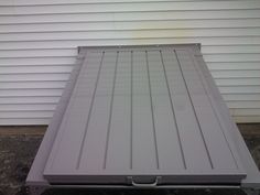 a flatbed truck bed sitting in front of a white garage building with siding on it