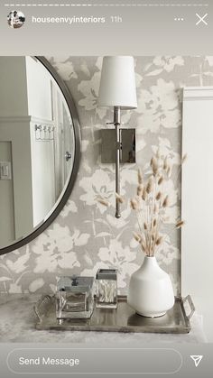 a white vase sitting on top of a table next to a mirror and lamp in a room