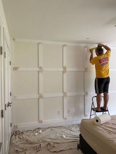 a man standing on a stepladder painting the walls in a room that is being remodeled