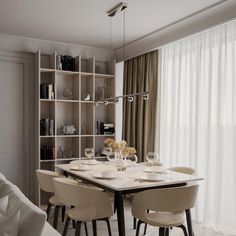 a dining room table and chairs in front of a bookshelf