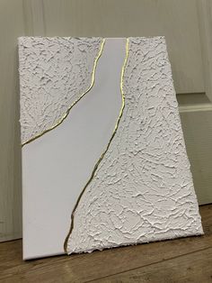 a white and gold painting sitting on top of a wooden floor