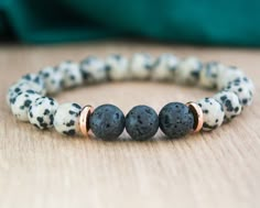 "Our Lava Stone and Dalmatian Jasper Bracelet is a beautiful accessory that offers more than just style. Made with 8 mm lava stones in the center, and Dalmatian Jasper beads, complemented by gold-colored stainless steel spacer discs, this bracelet is designed to help you stay grounded and balanced throughout your day. The beads are strung on a durable stretch cord, allowing for easy on/off fit. The finishing knot is not visible on this item. Whether you're looking for a unique piece of jewelry to add to your collection or a meaningful gift for someone special, this bracelet is sure to impress. Designed to be a perfect gift for her whether you're by her side or miles apart. Your jewelry will arrive in organza bag and gift box. If you want the jewelry with a gift card (see last photo) indica Bohemian Lava Stone Bracelets For Gift, Adjustable Lava Stone Stretch Bracelet Gift, Bohemian Lava Stone Bracelet As Gift, Spiritual Lava Stone Stretch Bracelet Gift, Bohemian Lava Stone Beaded Bracelets Gift, Bohemian Lava Stone Beaded Bracelet Gift, Lava Stone Bracelets With Natural Stones For Gift, Gift Bracelets With Natural Lava Stones, Dalmatian Jasper Bracelet