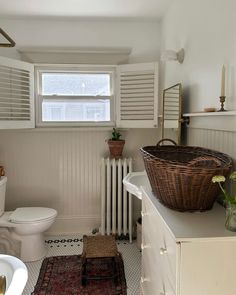 a bathroom with a basket on the counter next to a toilet and sink in it