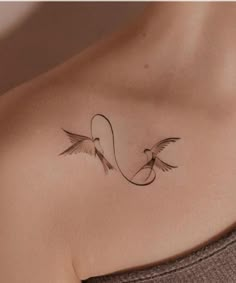 a woman's chest with two birds on top of it and an arrow in the middle