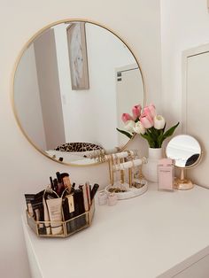 a white dresser topped with a mirror and lots of cosmetic items on top of it