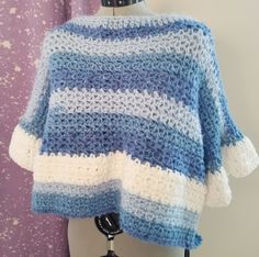 a blue and white crocheted sweater hanging on a mannequin's dummy