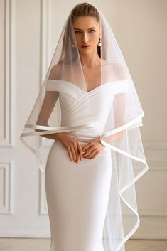 a woman in a white wedding dress with a veil on her head